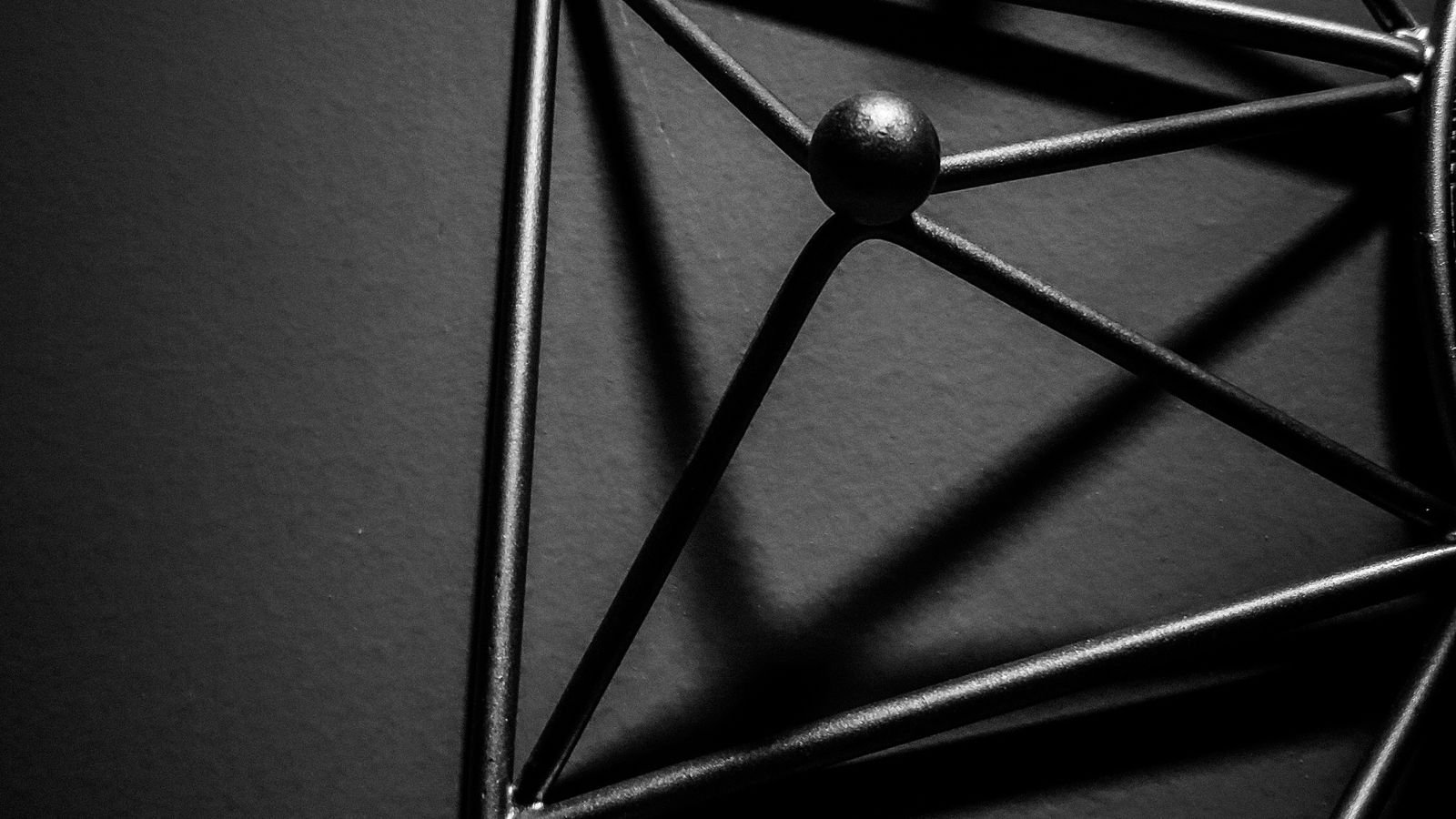 Geometrinen metallinen muoto ja varjot tummalla taustalla